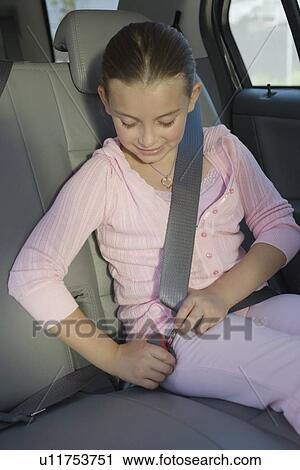 Stock Image - Girl fastening seatbelt in car. Fotosearch
