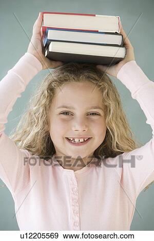 Girl holding stack of books on head View Large Photo Image Stock Photo - Girl holding stack of books on head. Fotosearch