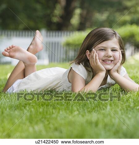 Stock Image - Girl laying in grass. Fotosearch