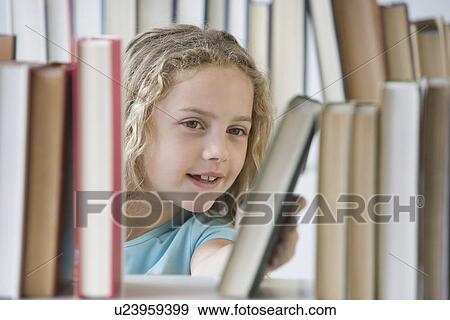 Girl looking at books on shelf View Large Photo Image Stock Photo - Girl looking at books on shelf. Fotosearch