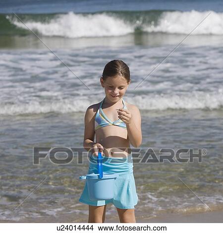 Girl looking at shell at beach View Large Photo Image Picture - Girl looking at shell at beach. Fotosearch