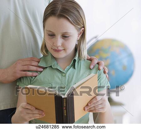 Stock Photography - Girl reading book next to father. Fotosearch