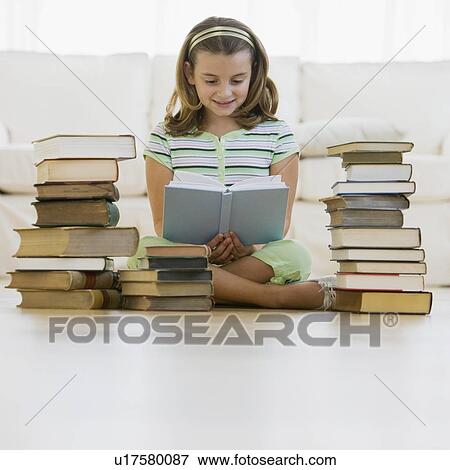 Stock Photo - Girl reading next to stacks of books. Fotosearch