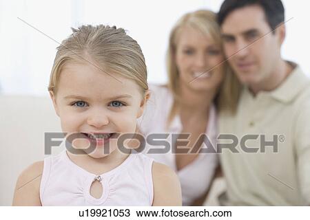 Stock Image - Girl smiling with parents in background. Fotosearch