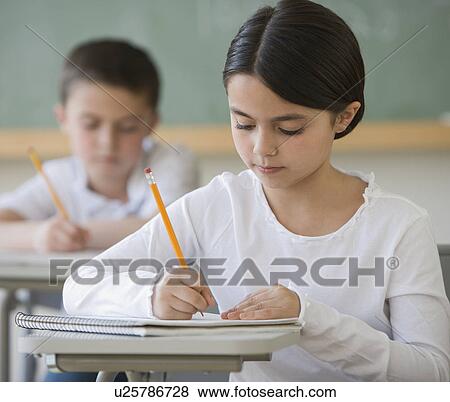 Girl writing at desk in classroom View Large Photo Image Stock Photo - Girl writing at desk in classroom. Fotosearch