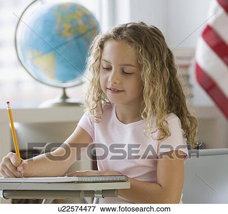 Stock Photo - Girl writing at school desk. Fotosearch