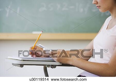Picture - Girl writing in classroom. Fotosearch