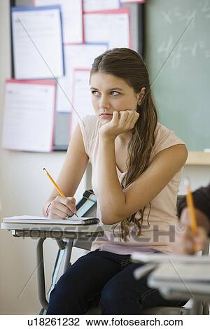 Stock Image - Girl writing in classroom. Fotosearch
