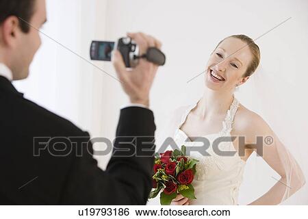 Stock Photograph - Groom video recording bride. Fotosearch