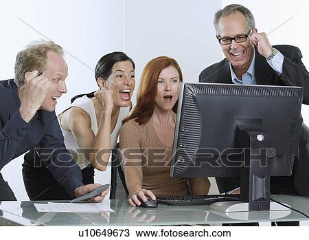 Stock Image - Group of businesspeople cheering with computer. Fotosearch