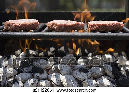 Stock Image - Hamburgers cooking on grill. Fotosearch