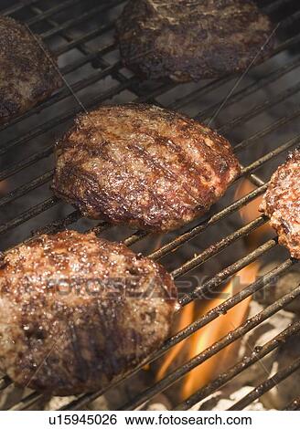 Stock Photograph - Hamburgers cooking on grill. Fotosearch