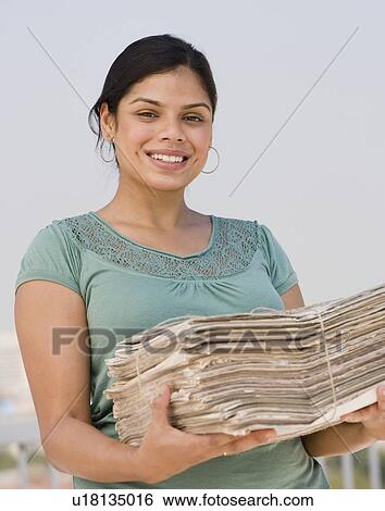 Stock Photograph - Hispanic woman holding stack of newspapers. Fotosearch