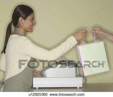 Indian female clerk handing shopping bag View Large Photo Image Stock Image - Indian female clerk handing shopping bag. Fotosearch