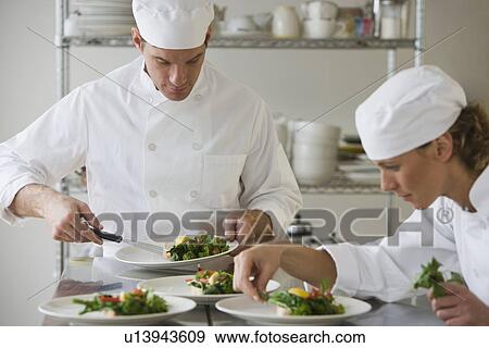 Stock Photo - Male and female chefs plating food. Fotosearch