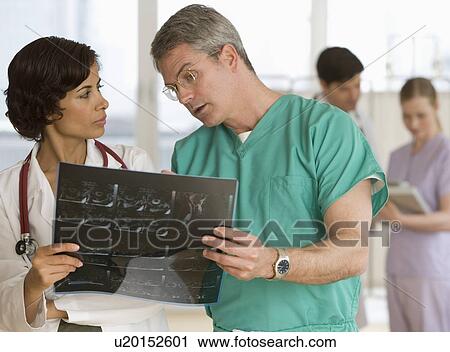 Stock Image - Male and female doctors looking at x-ray. Fotosearch