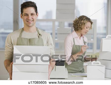 Stock Photography - Male bakery worker carrying stack of boxes. Fotosearch