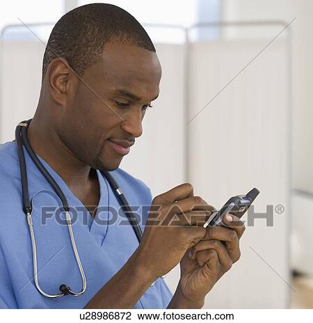 Stock Image - Male doctor using electronic organizer. Fotosearch