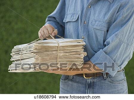 Man carrying bundle of newspapers View Large Photo Image Picture - Man carrying bundle of newspapers. Fotosearch