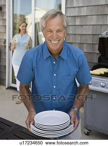 Stock Image - Man carrying stack of plates. Fotosearch