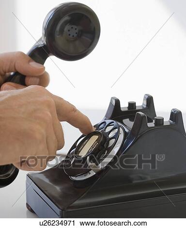 Stock Image - Man dialing rotary telephone. Fotosearch