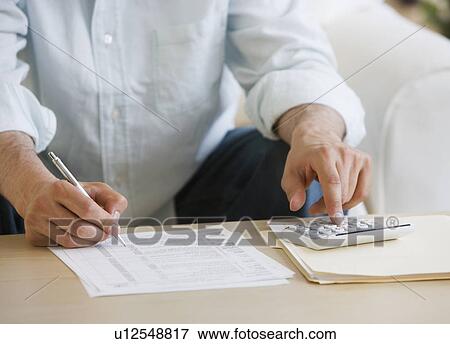 Stock Photo - Man doing taxes at home. Fotosearch