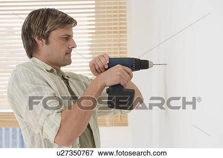 Stock Photo - Man drilling hole in wall. Fotosearch