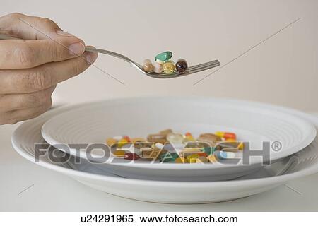 Stock Photography - Man eating pills on fork. Fotosearch