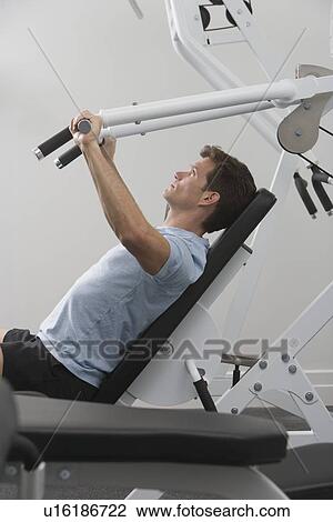 Stock Image - Man exercising at gym. Fotosearch