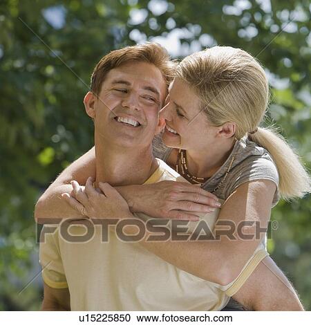 Stock Image - Man giving wife piggyback ride. Fotosearch