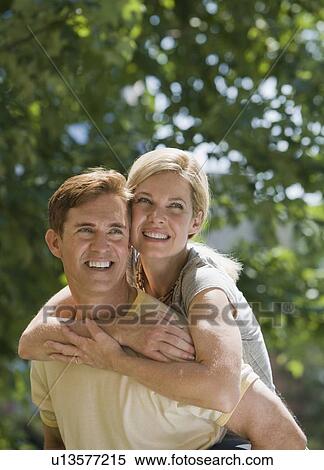 Stock Photography - Man giving wife piggyback ride. Fotosearch