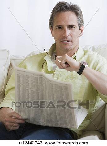 Man holding newspaper on sofa View Large Photo Image Stock Image - Man holding newspaper on sofa. Fotosearch
