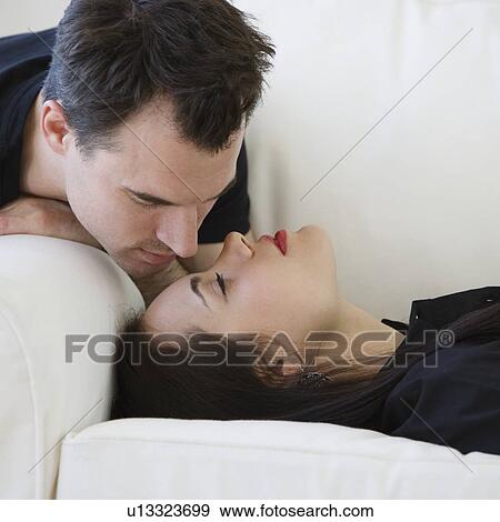 Man leaning over girlfriend on sofa View Large Photo Image Stock Photo - Man leaning over girlfriend on sofa. Fotosearch
