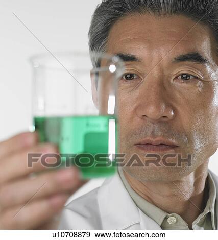 Man looking at beaker of fluid View Large Photo Image Stock Photo - Man looking at beaker of fluid. Fotosearch