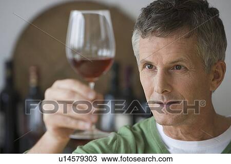 Stock Image - Man looking at glass of wine. Fotosearch