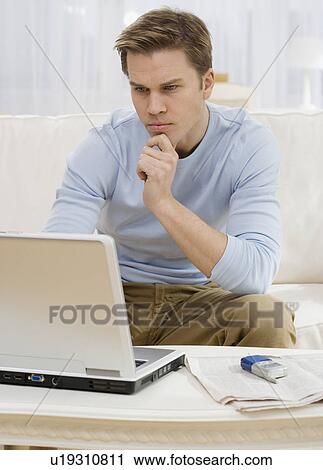 Man looking at laptop on sofa View Large Photo Image Stock Image - Man looking at laptop on sofa. Fotosearch