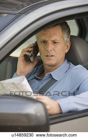 Stock Image - Man looking at map in car. Fotosearch
