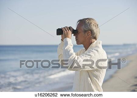 Stock Image - Man looking through binoculars. Fotosearch