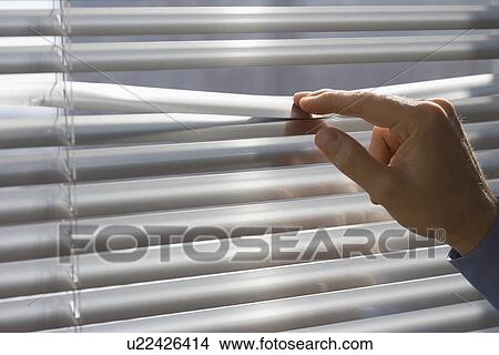 Picture - Man looking through blinds. Fotosearch