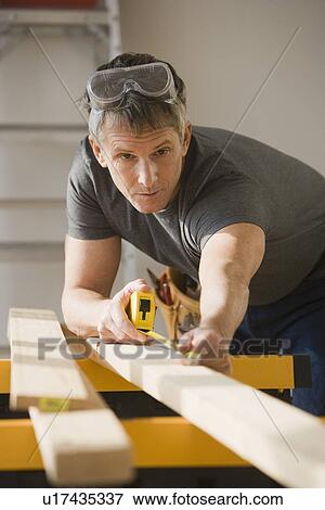 Man measuring piece of wood View Large Photo Image Stock Photo - Man measuring piece of wood. Fotosearch