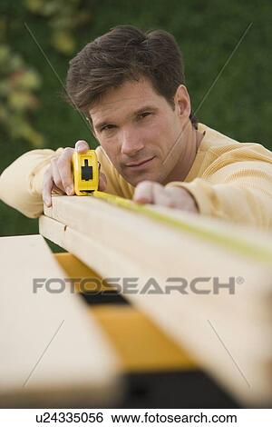 Man measuring piece of wood View Large Photo Image Stock Photograph - Man measuring piece of wood. Fotosearch