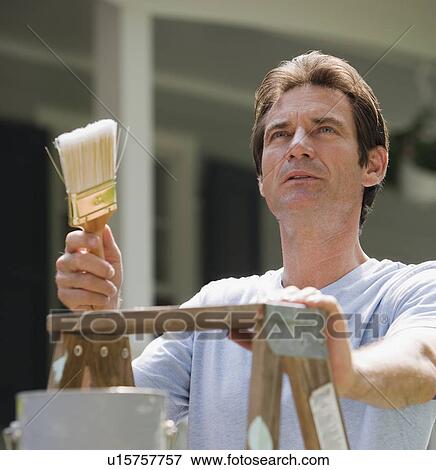 Stock Photo - Man on ladder with paintbrush. Fotosearch