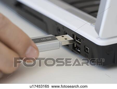 Stock Photography - Man plugging USB stick into laptop. Fotosearch