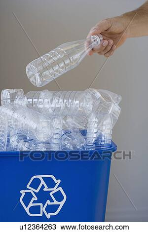 Stock Image - Man putting bottle in recycling bin. Fotosearch