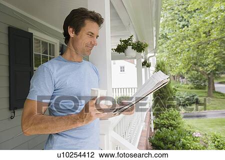 Stock Image - Man reading newspaper on porch. Fotosearch