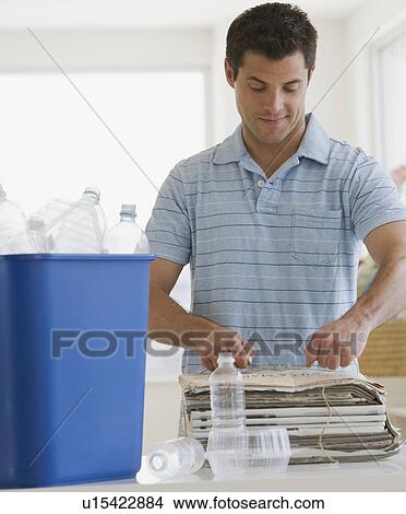 Picture - Man recycling newspaper and plastic. Fotosearch