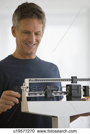 Stock Image - Man standing on scale. Fotosearch