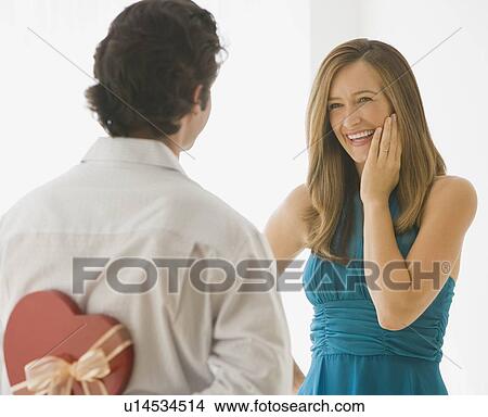 Picture - Man surprising wife with valentine’s day gift. Fotosearch