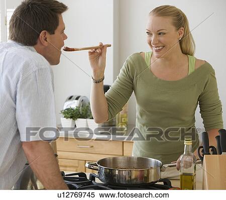 Stock Photography - Man tasting food in kitchen. Fotosearch