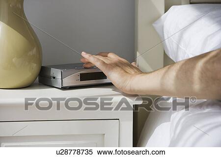 Man touching alarm clock from bed View Large Photo Image Stock Photography - Man touching alarm clock from bed. Fotosearch